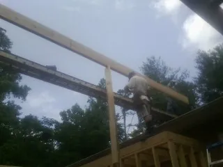 Carpenter setting a ridge beam over a new addition frame — Ice Dam Removal by Roofing Brothers in Gum Spring