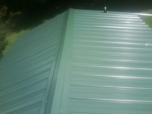 New green metal panels meeting at the ridge of a roof — Flat Roof Repair work by our crew in Gum Spring