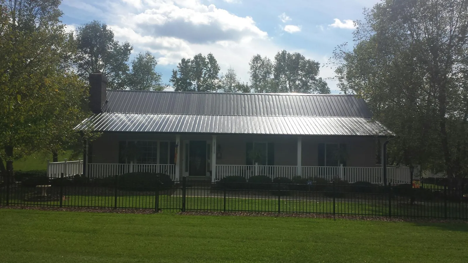 Gray metal roof on a brick ranch with a full width front porch — Gutter Guard Installation work by our crew in Gum Spring