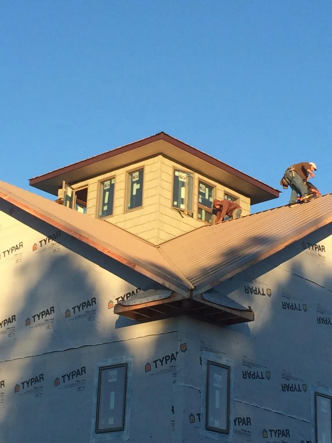 Roofers working around a rooftop cupola on a new metal roof at sunset — Roof Waterproofing in Gum Spring by Roofing Brothers